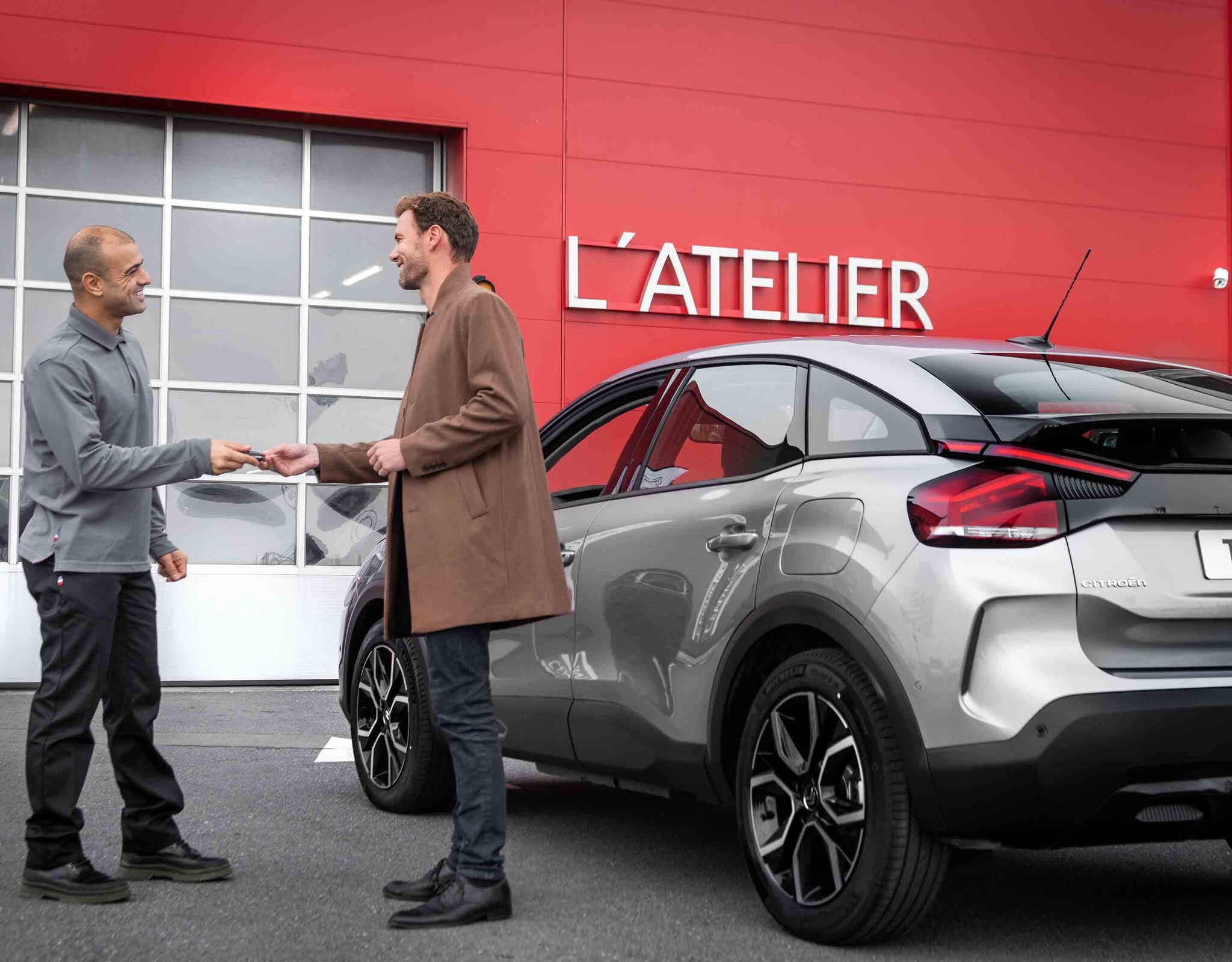 Technicien Citroën et client près de ë-C4 Electrique garée devant l'Atelier Citroën